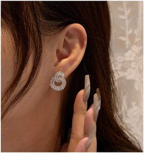 Macro view of interlocking double circle earrings with cubic zirconia on model's ear