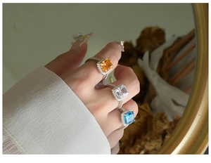 Radiant cut gemstone rings in yellow, blue, and clear colors with silver halo setting