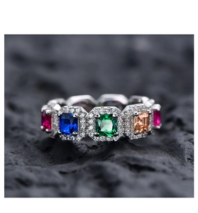 Makroaufnahme von Silberring mit bunten quadratischen Edelsteinen und Diamanthalo auf Stein