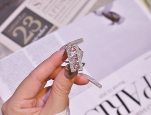 Macro shot of silver bridge ring with pink round zircons and white pave settings