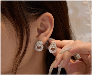 Close-up of double-circle silver stud earrings with sparkling trapezoid and round zircon