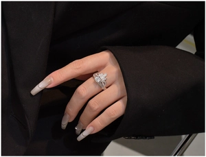 Macro detail of silver crown clover ring with zircon stones worn by a model