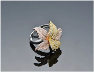 Macro view of three-tone leaf rings with sparkling cubic zirconia pavé on black background