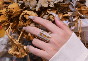 Macro detail of geometric sterling silver ring featuring three round amber stones on finger