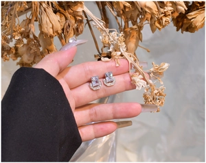U-shaped sterling silver earrings with rectangular cut zircon held in hand for scale