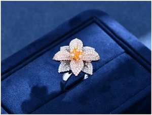 Dettaglio macro di anello a fiore tricolore con pietre su velluto blu scuro