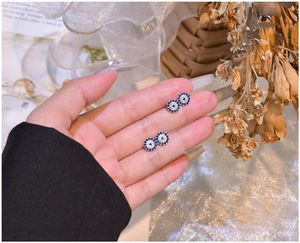 Detailed view of S925 silver blue zircon evil eye stud earrings held in hand