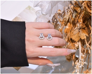 Detail view of silver U-shaped earrings with rectangular cubic zirconia held by hand