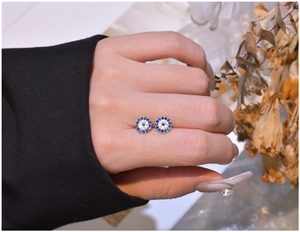 Macro detail of gold S925 silver evil eye stud earrings with blue and white zircons