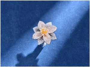 Dettaglio macro di un anello a fiore in argento 925 con micro-pavé di cristalli e centro giallo