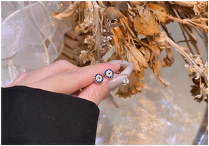 Macro shot of silver stud earrings featuring blue and white zircon evil eye design