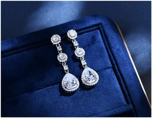 Detailed view of pear-cut crystal drop earrings in S925 silver on dark velvet box