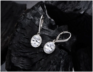 Macro shot of 925 silver oval-cut crystal earrings on textured charcoal background