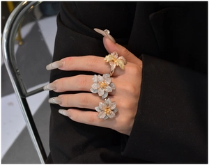 Detailed view of stacked S925 silver flower rings with gold finish and pavé crystals