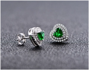Detailed macro view of heart-shaped emerald stud earrings with double halo micro-pave setting