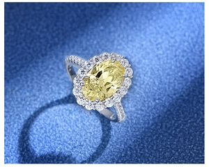 Top view of large oval yellow stone ring with halo diamond setting and silver band