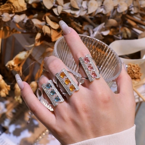 Three rectangular 925 sterling silver rings set with colorful stones on female fingers