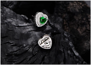 Detail showing S925 sterling silver stamp and heart emerald earrings on dark wood
