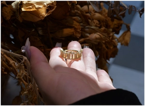 Detailed view of a gold crown ring with pavé-set crystals held in hand for a retro look