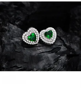 Detailed macro view of heart-shaped emerald stud earrings with double halo zirconia stones