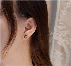Close-up of a blue zircon halo stud earring worn on a model ear with lace background