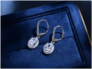 Close-up of 7x9mm oval cut crystal earrings in 925 silver setting with halo design