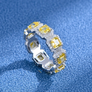 Ring mit gelben Smaragdschliff-Edelsteinen und weißem Diamant-Halo auf blauem Grund