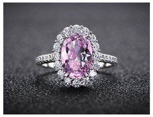 Macro shot of oval-cut pink gemstone ring with halo diamond setting and silver band