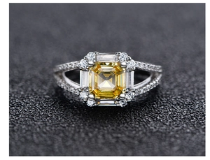 Macro shot of Asscher cut yellow gemstone ring with silver split-shank band and halo diamonds