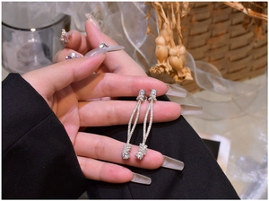 Detailed view of sterling silver knot tassel earrings with micro-pave zirconia crystals