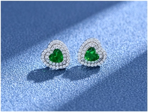 Detail of heart-shaped emerald stud earrings in S925 sterling silver with double halo