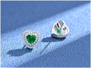 Macro detail of heart-shaped emerald stud earrings with double halo zircon in S925 silver