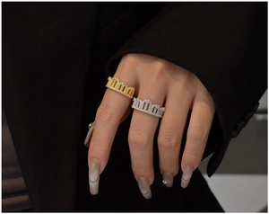 Detailed view of silver and gold crown rings with white pavé zircons on finger