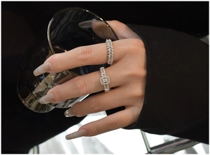 Detail of S925 silver stacked rings with cubic zirconia stones on hand holding glass