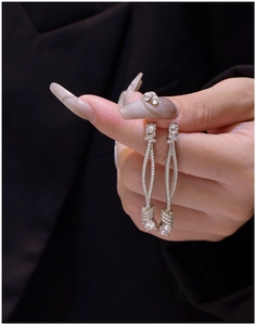 Macro shot of 925 silver knotted tassel earrings with micro-pave crystals on fabric