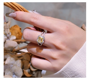Close-up of radiant yellow Asscher cut gemstone ring on finger with pave crossover band