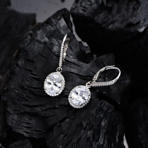 Classic 925 silver halo drop earrings with oval 7x9mm stones on textured rock background