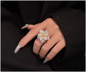 Macro shot of tiered flower ring with silver and gold petals and a yellow center stone