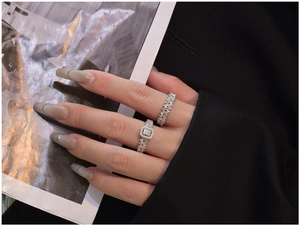 Detailed view of silver rings set with a belt buckle design and sparkling zircons