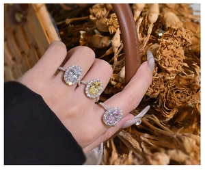 Detailed view of three halo-set oval gemstones in white yellow and pink on a S925 silver band