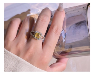 Detail of yellow Asscher cut ring with diamond halo and crisscross band on hand