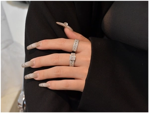 Detail of 925 silver rings set with rectangular zircon worn on a black suit background