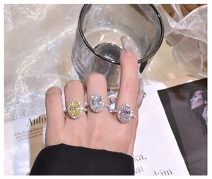 Three halo oval-cut rings with pink, yellow and clear stones worn on fingers