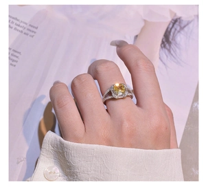 Macro shot of Asscher cut yellow gemstone ring with pavé diamond band on a lifestyle setting