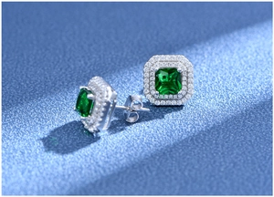 Macro shot of square emerald cut green stone stud earrings with double halo pave