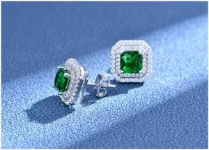 Macro shot of square emerald earrings with double halo diamonds and silver setting