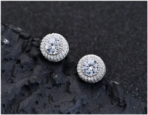 Vue détaillée de boucles d'oreilles halo en argent avec pavé de zircons sur roche volcanique