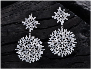 Macro shot of silver snowflake earrings with sparkling zircon stones on dark wood