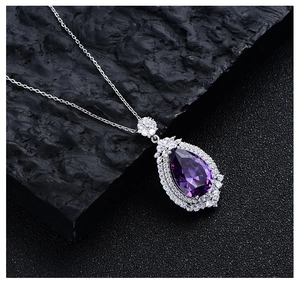Macro detail of pear-shaped purple crystal pendant with double halo diamond setting