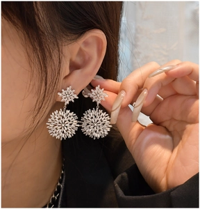 Close-up of S925 sterling silver snowflake earrings with sparkling zircon on ear